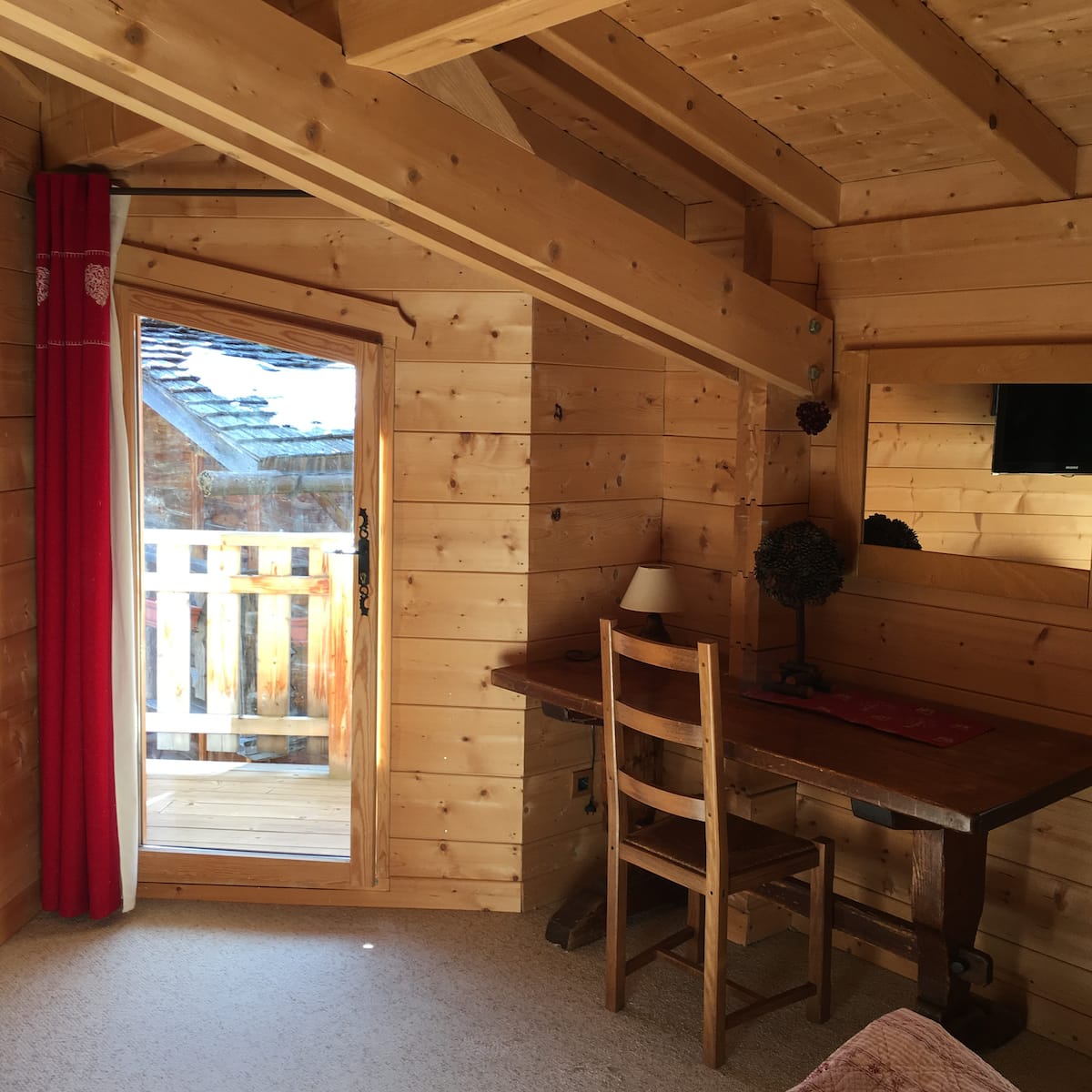 Le bureau du chalet avec sa table en bois massif et sa porte ouvrant sur une terrasse privative