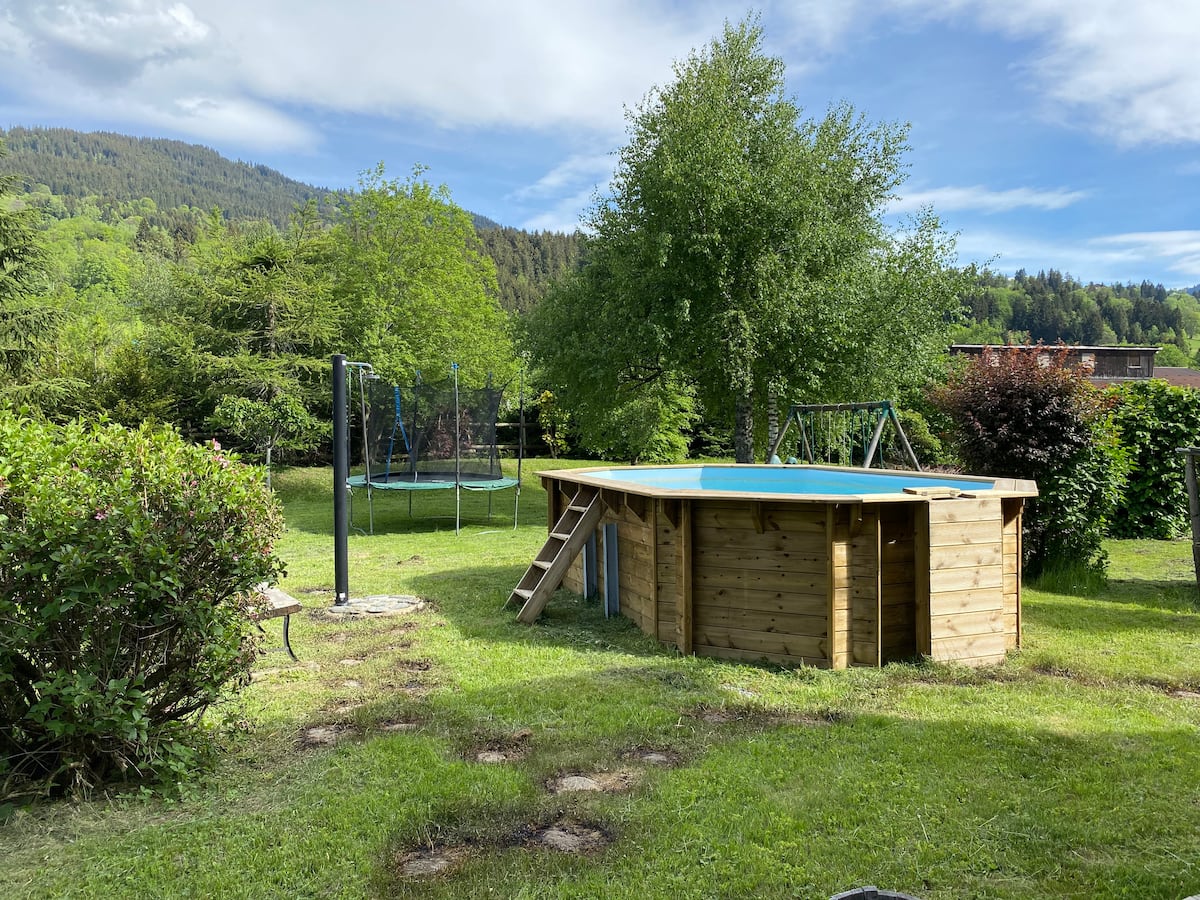 La piscine hors sol en bois et le trampoline dans le jardin du chalet