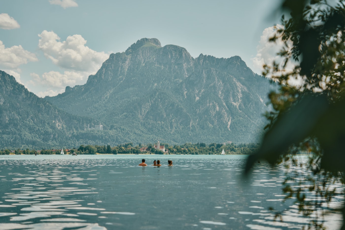 Baigneurs dans un plan d'eau naturel de montagne, sommet et sapins en arrière-plan