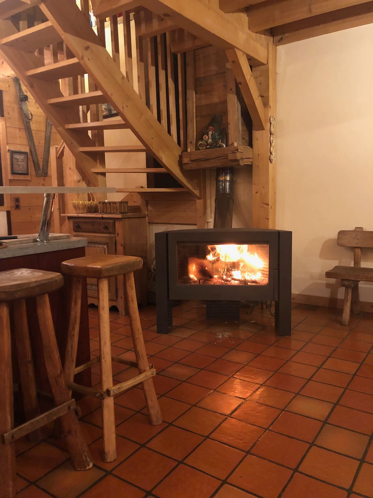 Le poêle-cheminée allumé au pied de l'escalier en bois du chalet