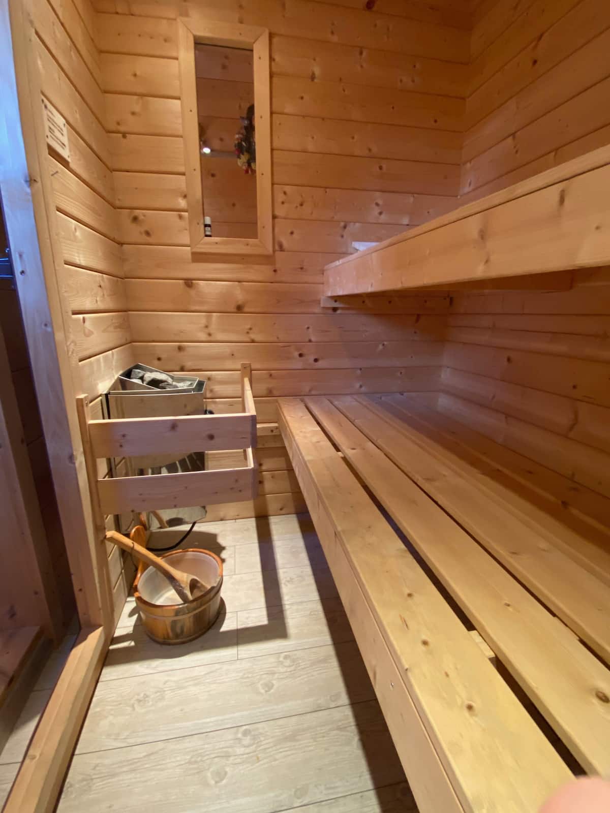 Le sauna privé du chalet, tout en bois clair avec son seau et sa louche